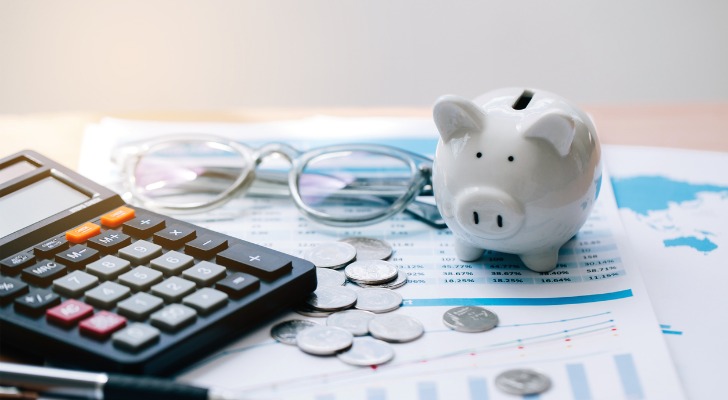 Closeup of a piggy bank and a calculator on top of a statement.