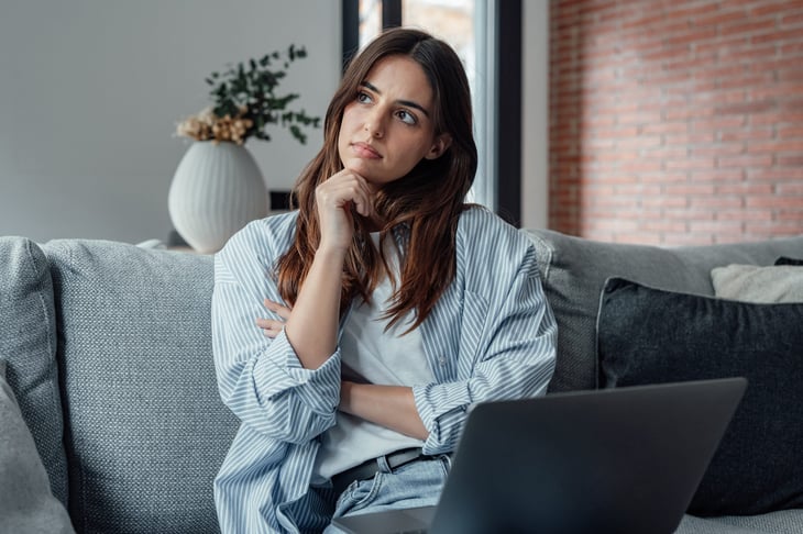 Woman pondering a question at a laptop