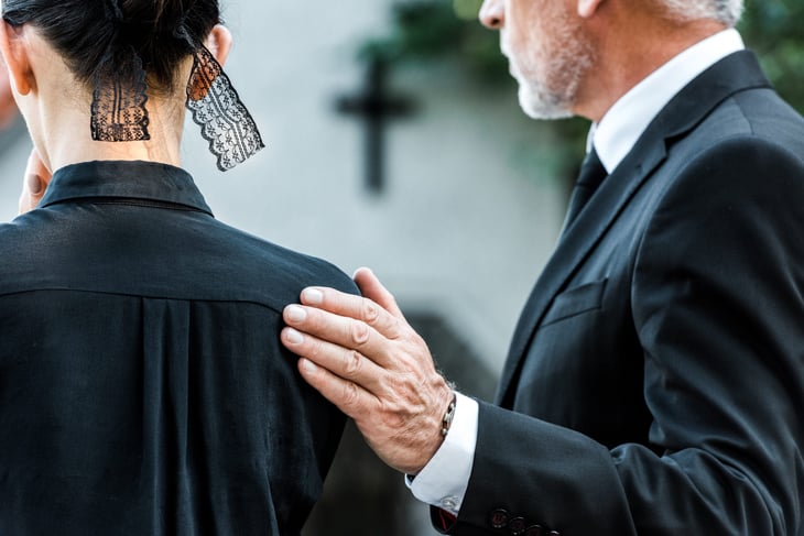 Grieving widow being comforted at a funeral service