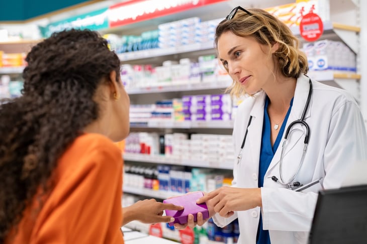 Pharmacist giving medication to a customer in a pharmacy.